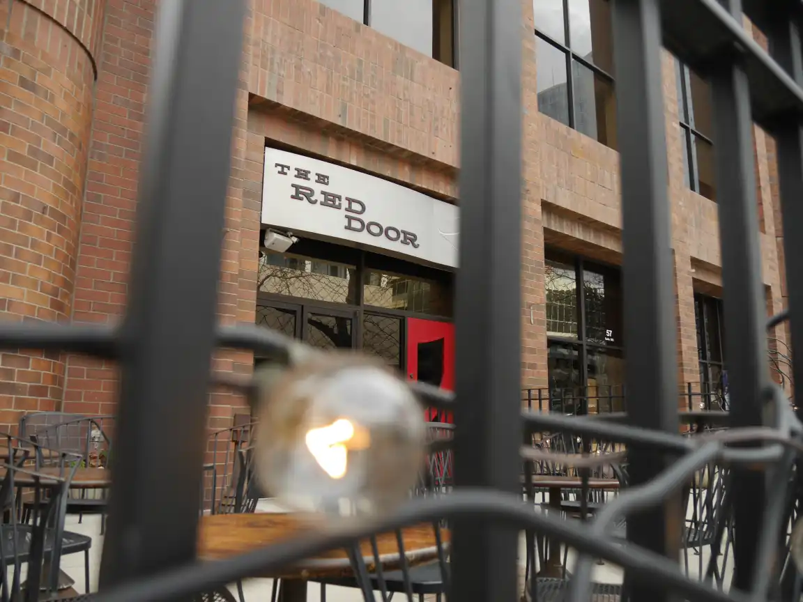 The Red Door sign framed by a fence and decorative light