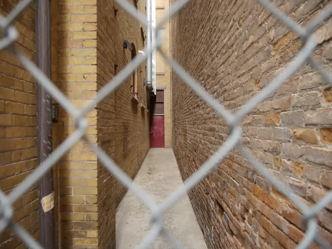 A red door framed by a chain-link fence