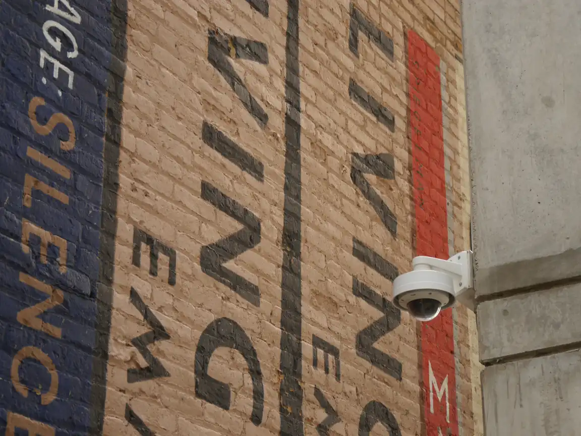 A security camera in front of a mural of books