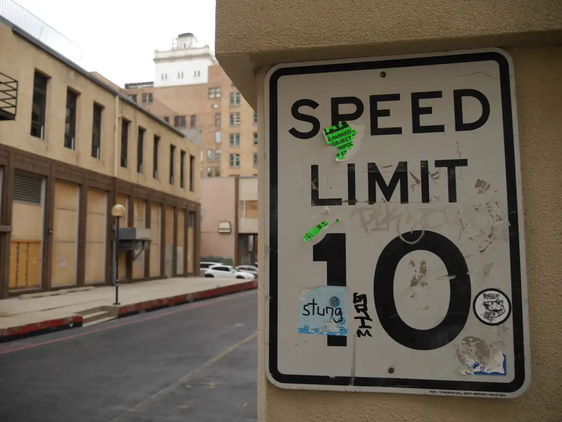 A 'SPEED LIMIT 10' sign with stickers and graffiti