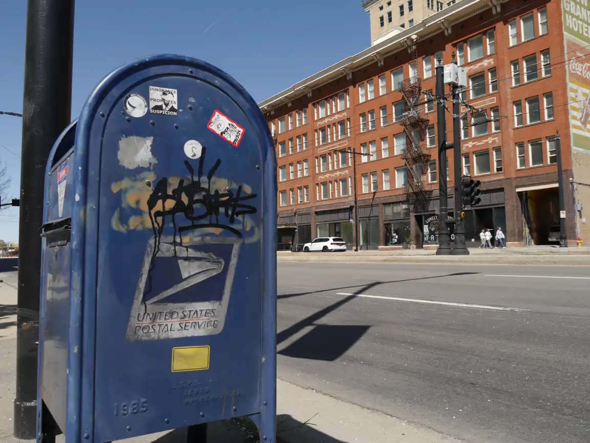 A USPS collection box in front of an old building