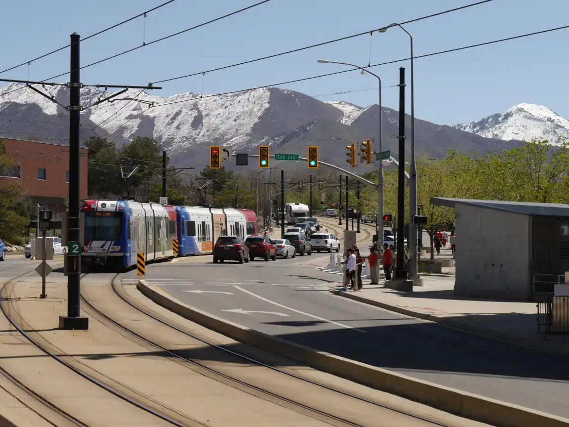 An exciting day northeast of the Rice-Eccles Stadium, featuring a Red Line train and a some fans walking about